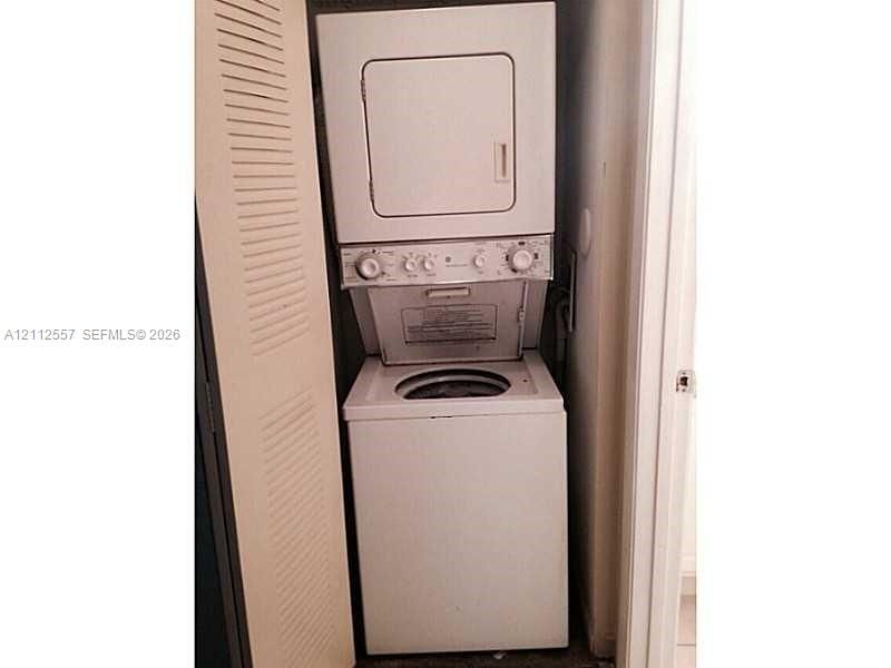 Stacked laundry center featuring a top-loading washer, front-loading dryer, and louvered closet door