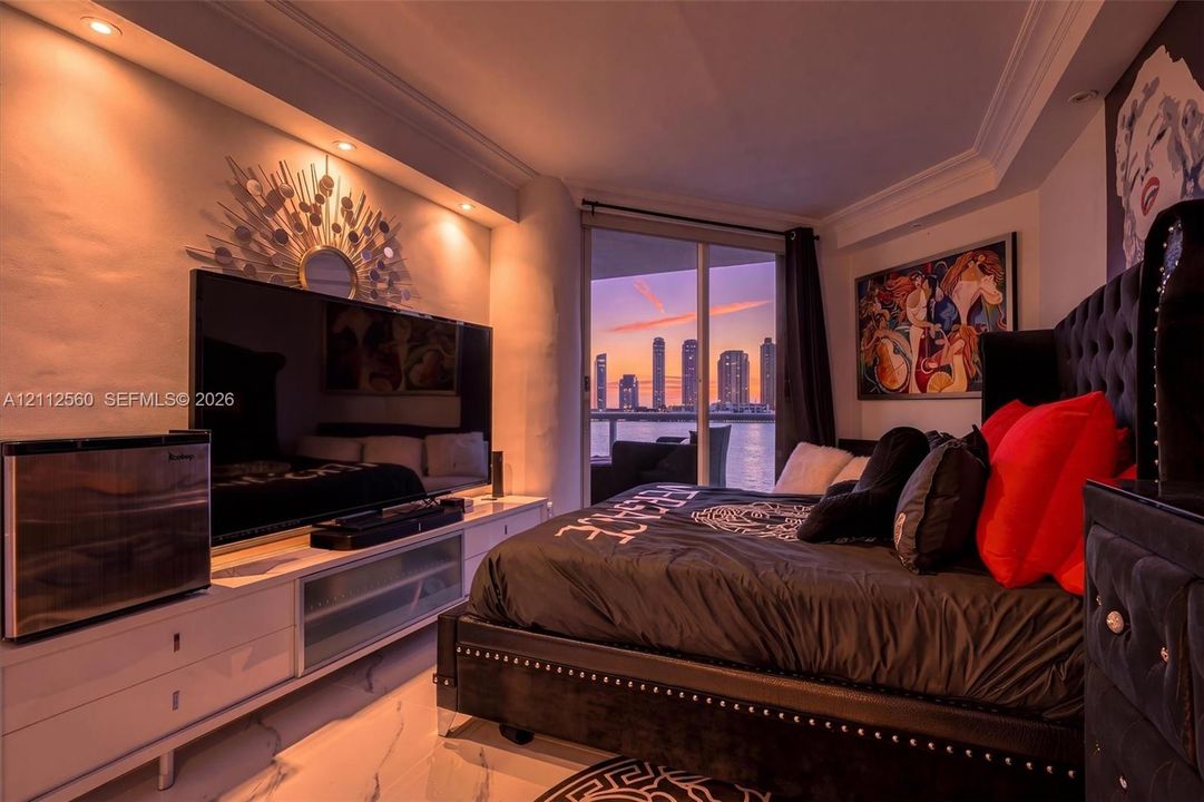 Custom built-in white cabinetry, recessed ceiling lighting, crown molding, polished stone flooring, and floor-to-ceiling glass sliding doors opening to a water-facing terrace