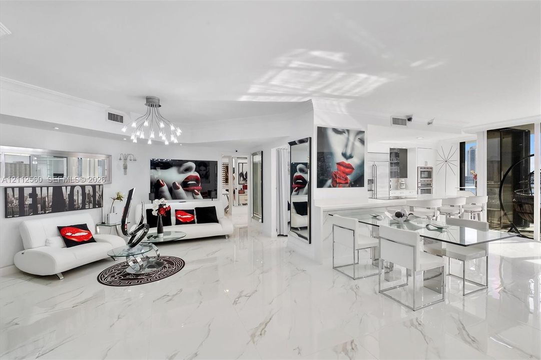 Open-concept living space featuring high-gloss large-format tile flooring, multi-arm chandelier lighting, sleek built-in cabinetry, and integrated kitchen appliances