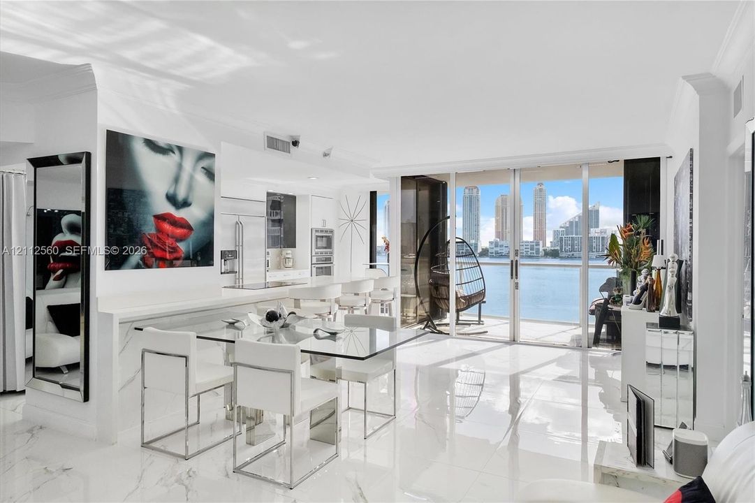 Open-concept living space featuring high-gloss stone-finish flooring, floor-to-ceiling glass sliding doors, and white cabinetry