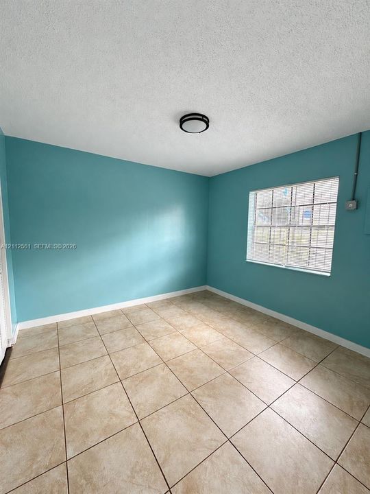 Interior room featuring large-format ceramic tile flooring, a multi-pane window with blinds, and a flush-mount circular ceiling light fixture