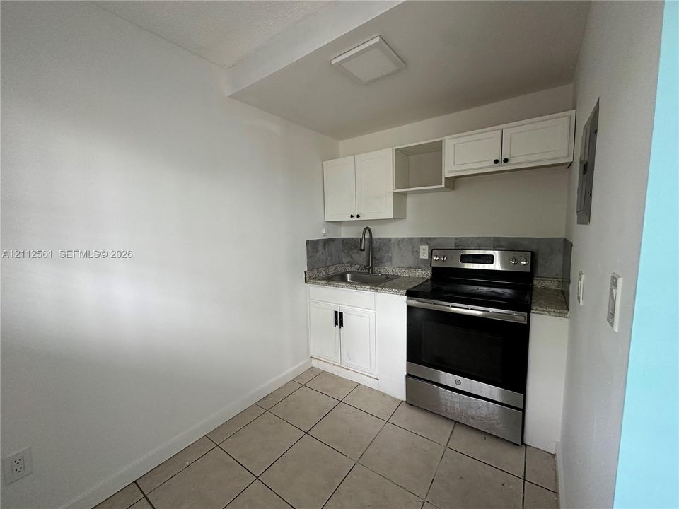 Kitchen featuring white cabinetry, stone-finish countertops, stainless steel range, gooseneck faucet, and tiled flooring