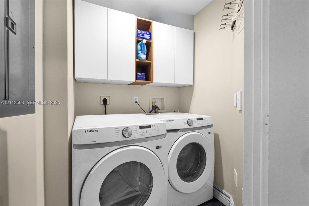 Laundry area featuring white cabinetry with integrated open shelving and dedicated appliance hookups