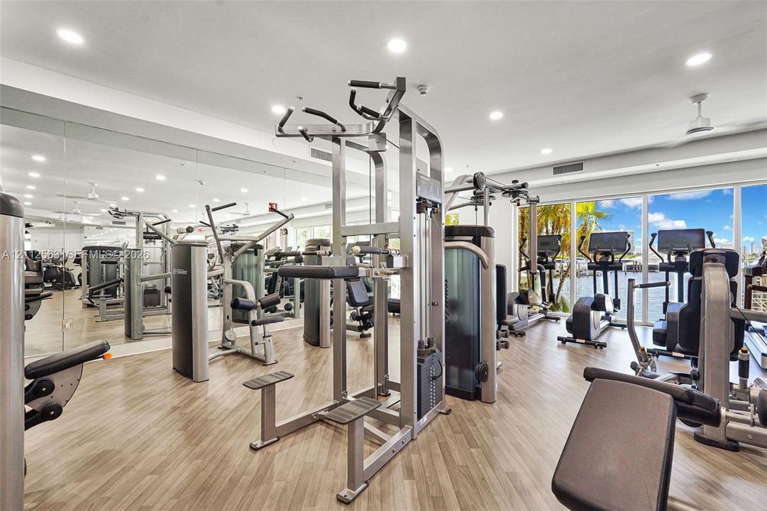 Fitness facility featuring full-wall mirrors, wood-finish flooring, recessed lighting, and floor-to-ceiling windows