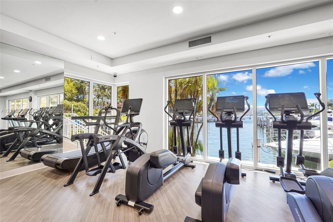 Fitness center featuring wood-finish flooring, floor-to-ceiling windows, and a full-wall mirror