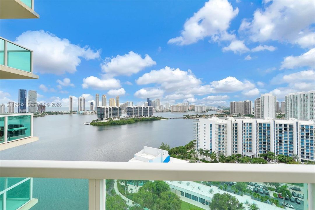 Covered balcony with glass railings, panoramic water and urban skyline backdrop
