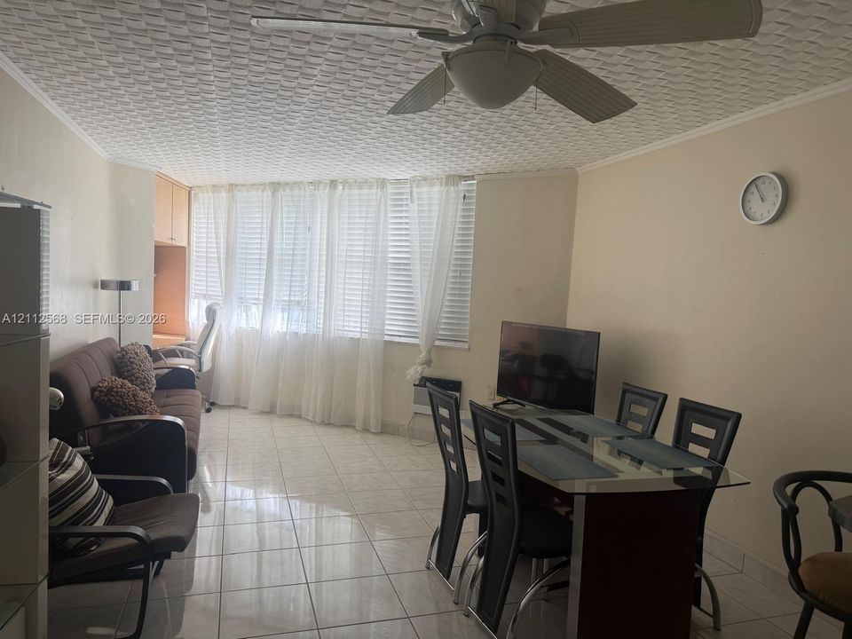 Large-format tile flooring, textured ceiling with integrated lighting, built-in cabinetry, and expansive window wall with integrated horizontal blinds
