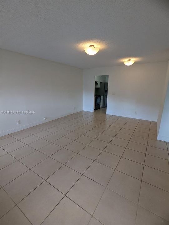 Neutral-toned ceramic tile flooring, textured ceiling finish, and dual flush-mount light fixtures