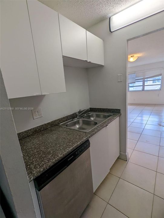 Kitchen featuring white cabinetry, stone-finish countertops, a double-basin stainless steel sink, and a stainless steel dishwasher