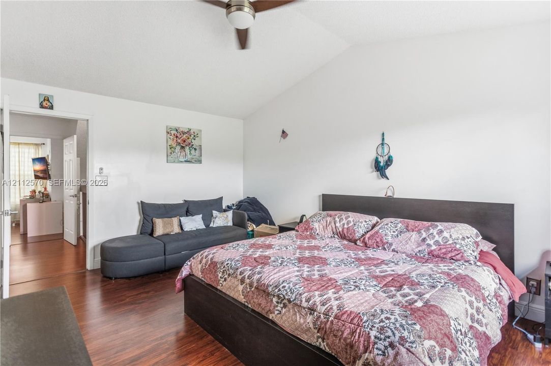 Vaulted ceiling, wood-finish flooring, and a ceiling fan with integrated lighting