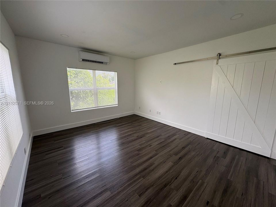 Interior space featuring wood-finish flooring, a wall-mounted ductless mini-split system, recessed lighting, and a white sliding barn door