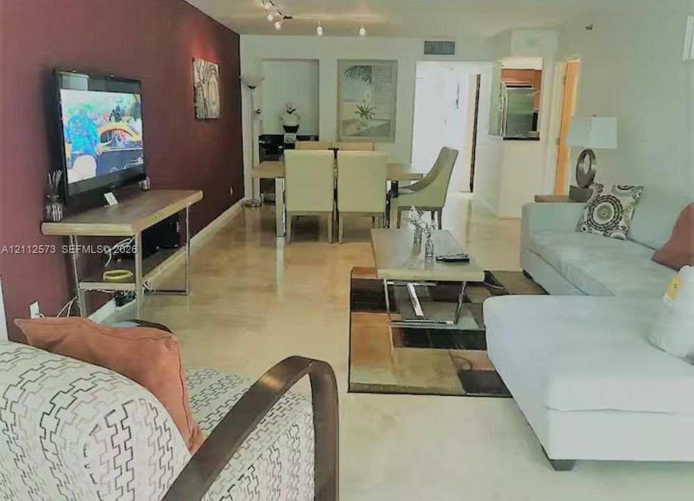 Open-concept interior featuring high-gloss polished stone flooring, a deep-toned accent wall, and recessed wall niches