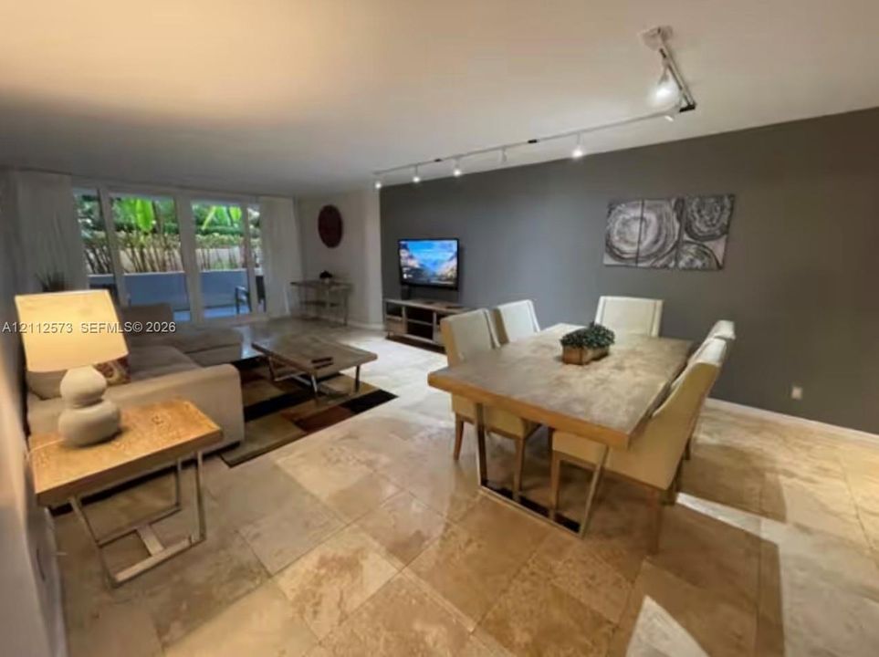 Spacious living area featuring large-format tile flooring, a prominent accent wall, and ceiling-mounted adjustable track lighting