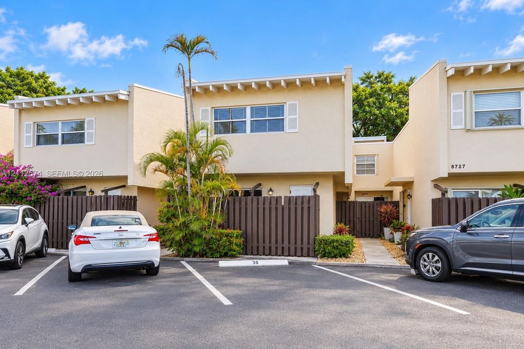 Stucco exterior featuring exposed rafter tails, private fenced courtyards, designated parking, and mature palm landscaping