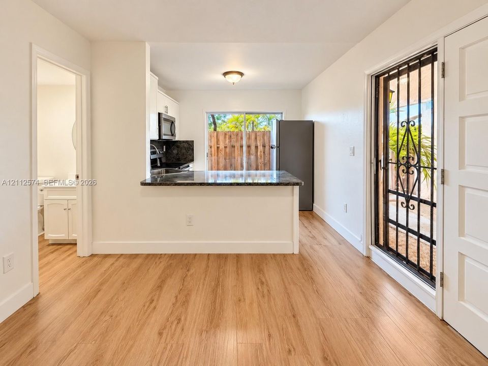 Kitchen featuring wood-finish flooring, stone-surfaced peninsula, and built-in cabinetry, including an exterior metal security door