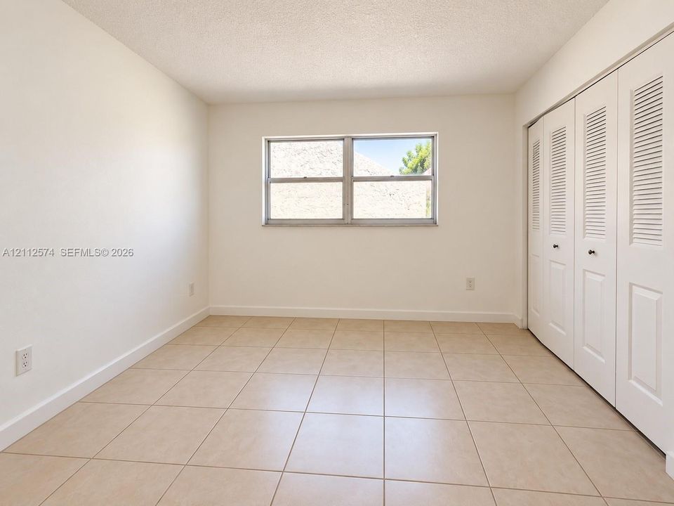 Neutral tile flooring, sliding louvered closet doors, and a double-pane horizontal window