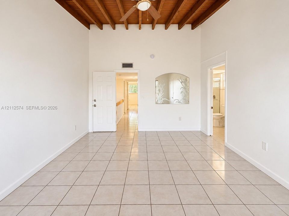 Exposed wood-beam ceiling, light-toned tile flooring, and integrated ceiling fan