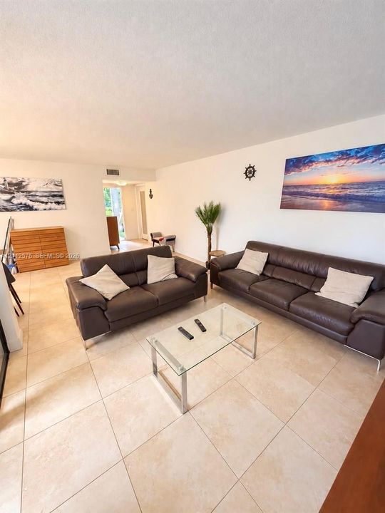 Open-concept interior featuring neutral ceramic tile flooring and smooth-finish ceilings
