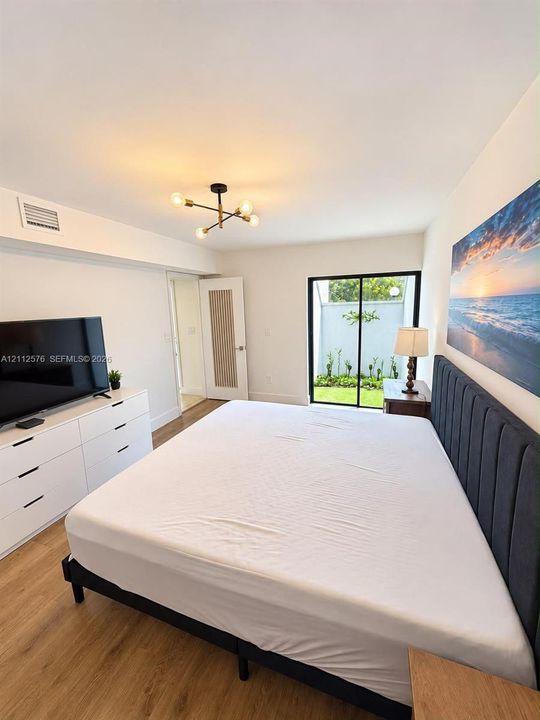 Wood-finish flooring, multi-arm flush-mount light fixture, sliding glass door, and interior door with vertical glass panel insert