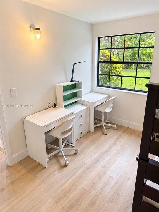 Wood-finish flooring, grid-pattern window with black framing, and a wall-mounted light fixture