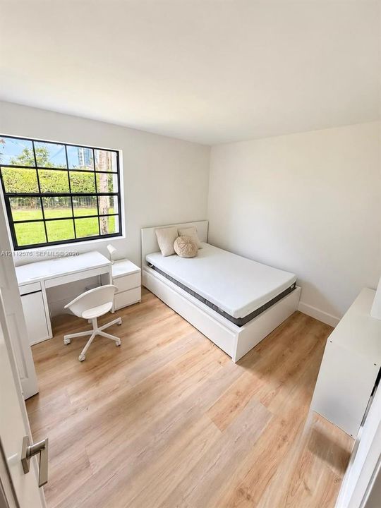 Room featuring wood-finish flooring, a grid-pattern window with a black frame, and neutral wall tones