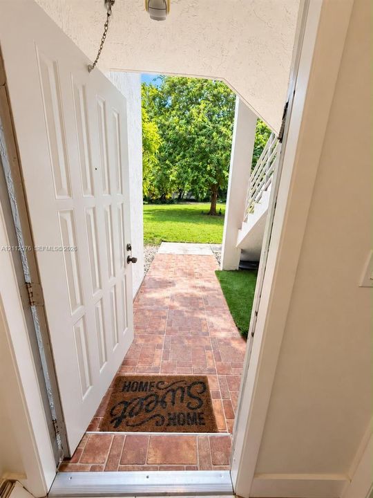 Covered entryway featuring tiled flooring, built-in staircase with railings, and access to a landscaped backyard