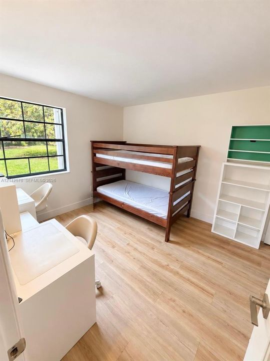 Room featuring wood-finish flooring, a large grid-pane window, and neutral wall color