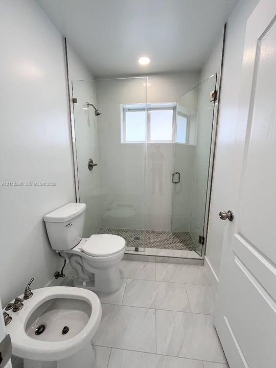 Walk-in shower featuring a frameless glass enclosure, patterned tile flooring, and metallic fixtures