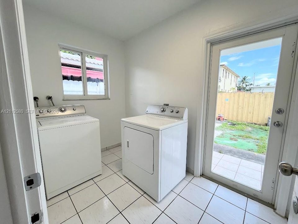 Laundry room featuring large-format ceramic tile flooring, a window, and a glass-paneled exterior door