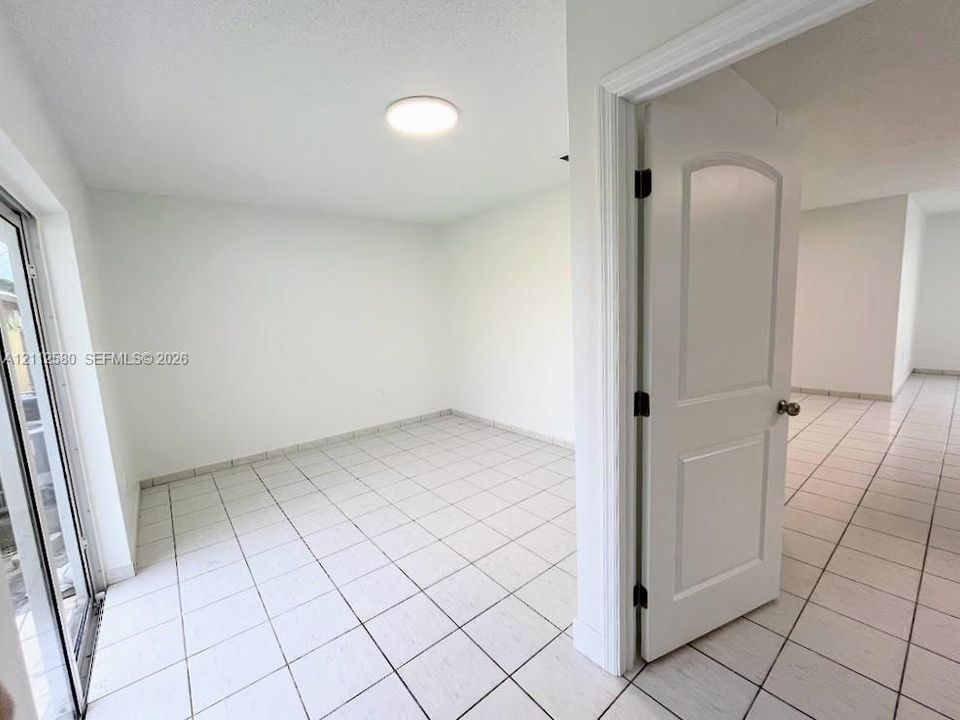 Interior room featuring ceramic tile flooring, a multi-panel arched interior door, a flush-mount ceiling light fixture, and a glass-paned door