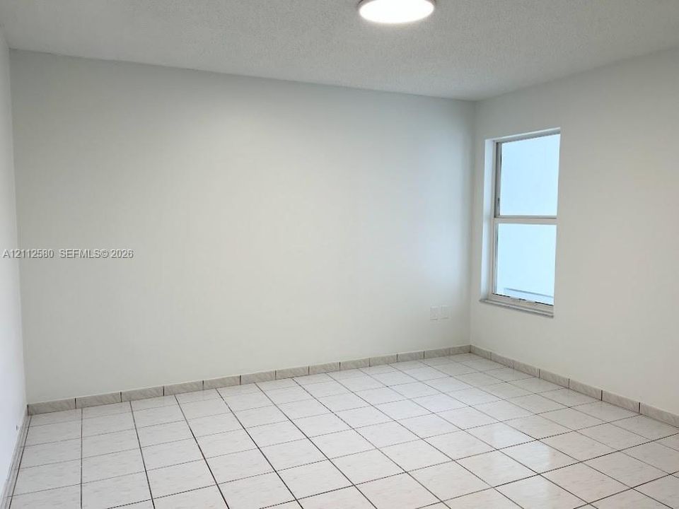 Neutral-toned interior space featuring ceramic tile flooring, a single-hung window, and a ceiling-mounted light fixture
