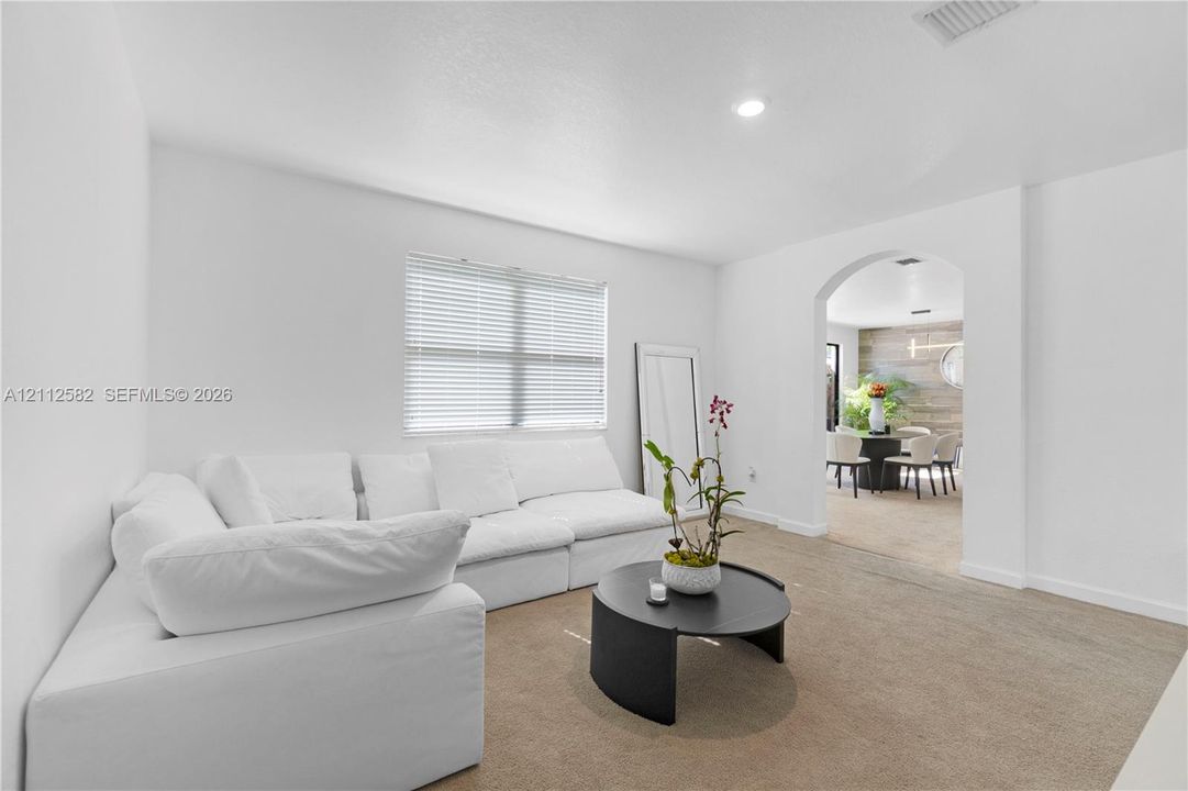 Neutral interior space featuring recessed lighting, a wide arched architectural opening, and horizontal window blinds