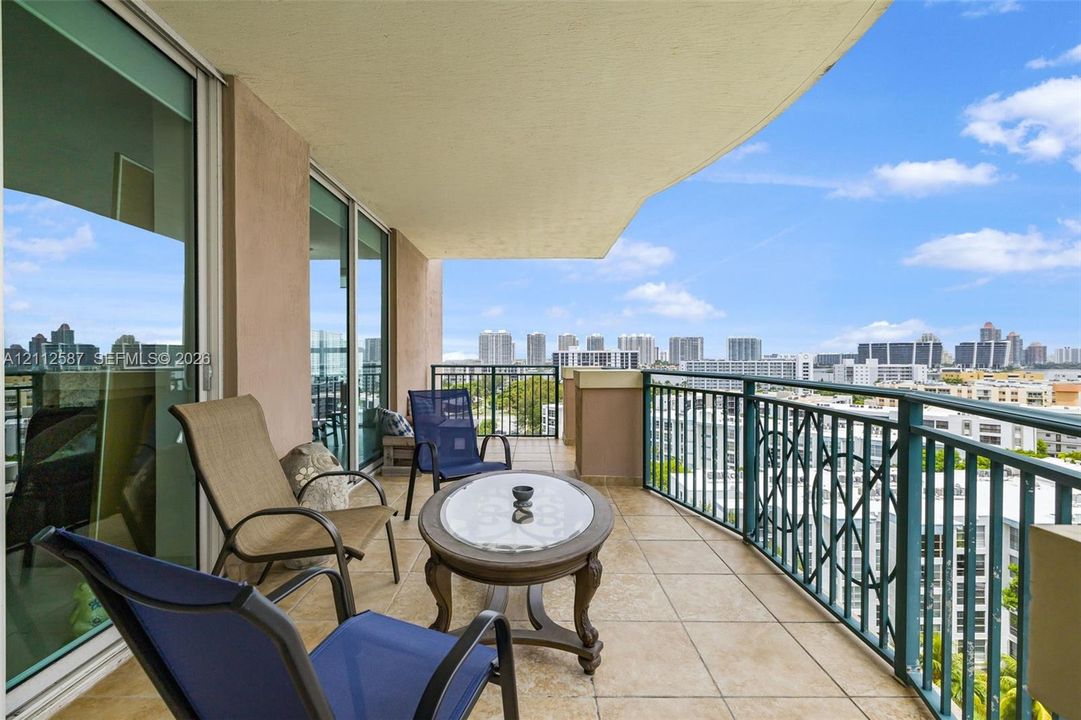 Covered balcony featuring tile flooring, decorative metal railing, and floor-to-ceiling sliding glass doors