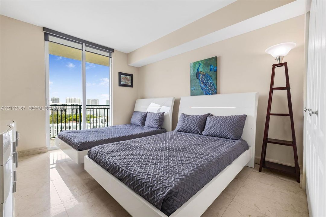 Light-filled room featuring large-format stone tile flooring, floor-to-ceiling sliding glass doors, and a private balcony with metal railing