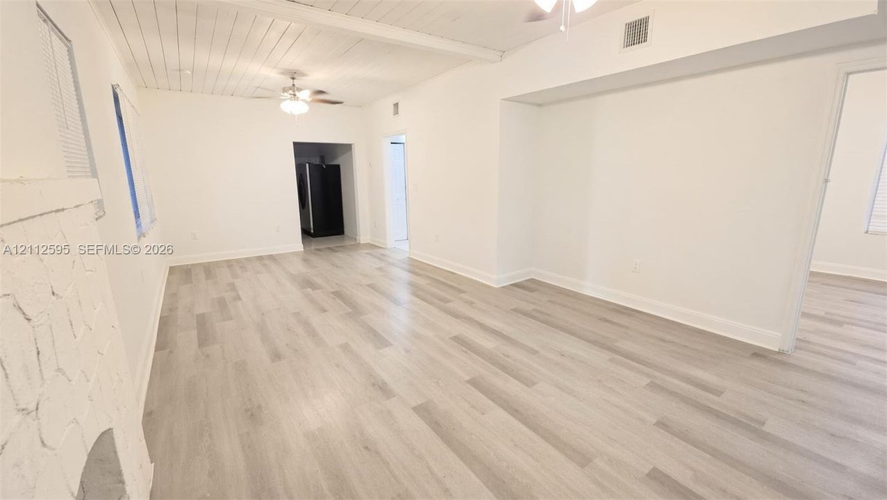 Interior space featuring wood-finish flooring, white-painted wood-plank ceiling, and a fireplace with a textured stone-finish surround