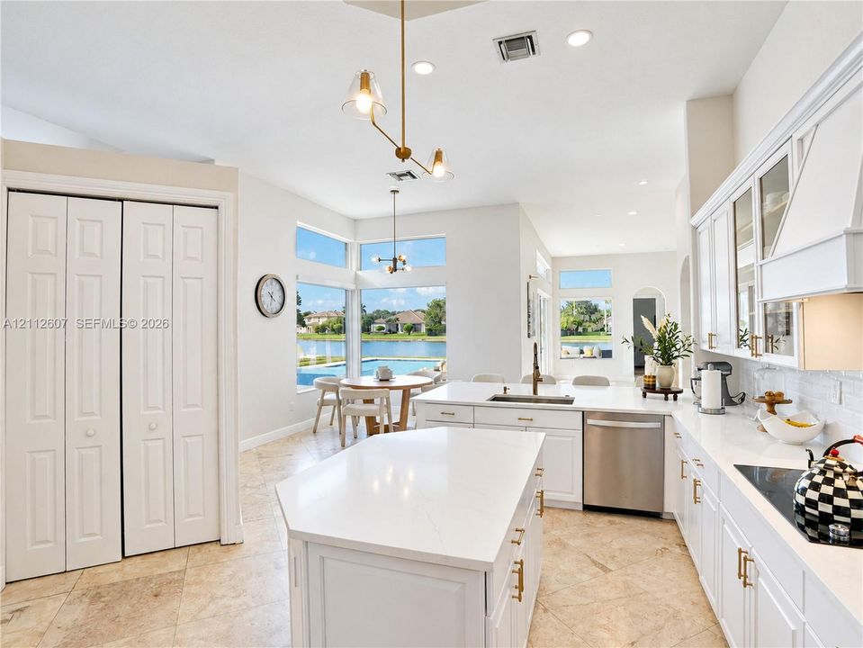 Kitchen featuring white cabinetry, center island with stone-finish countertops, stainless steel appliances, tile flooring, and floor-to-ceiling windows