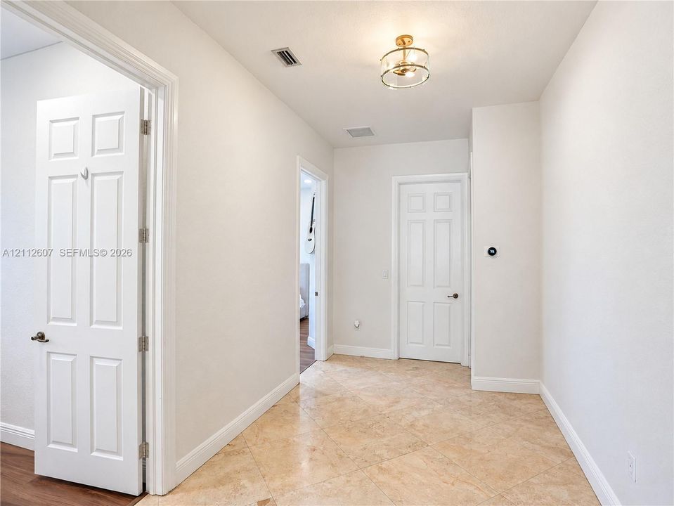 Hallway featuring diagonal-set tile flooring, multi-panel doors, and a decorative drum-style ceiling light fixture
