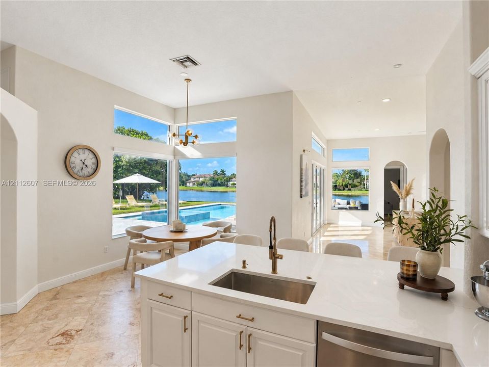 Kitchen featuring stone flooring, white cabinetry, a quartz countertop, an undermount stainless steel sink with a metallic faucet, and expansive floor-to-ceiling windows