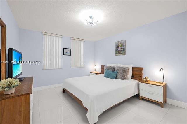 Neutral-toned walls, high-gloss tile flooring, vertical window blinds, and a multi-bulb flush-mount ceiling light fixture