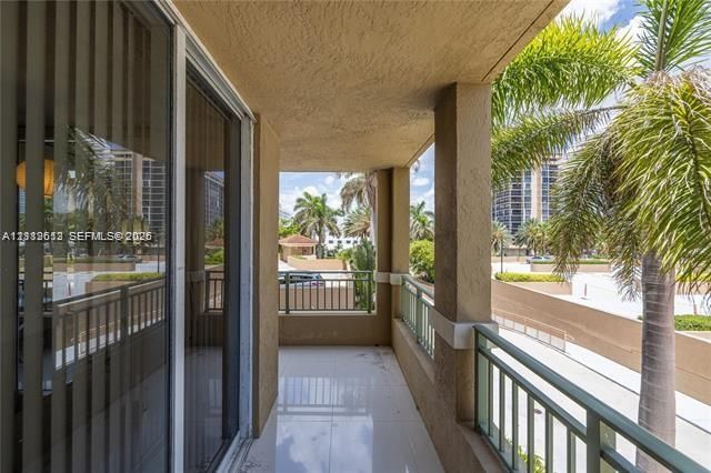 Covered balcony featuring tile flooring, metal railings, and a stucco ceiling