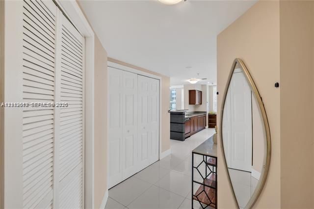 Interior area featuring high-gloss tile flooring, white bi-fold closet doors, and recessed ceiling lighting