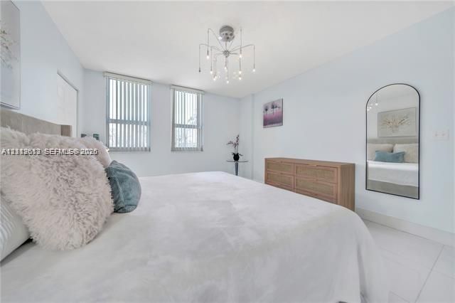 Bright room featuring light-toned flooring, multi-pane windows with vertical blinds, a contemporary sputnik-style chandelier, and an arched wall-mounted mirror