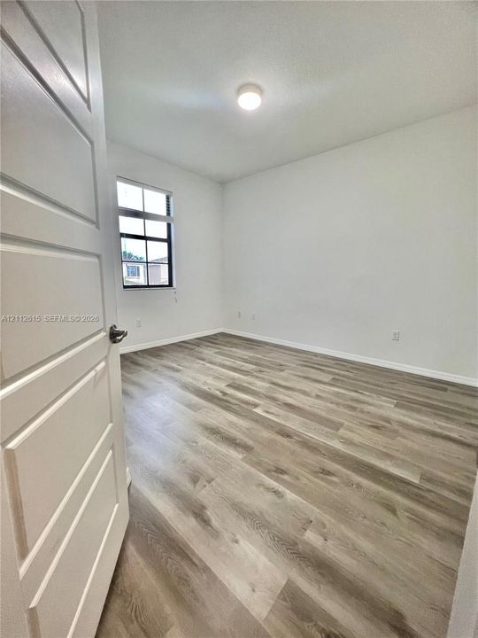 Interior space featuring wood-finish flooring, a multi-pane window, and a multi-panel interior door