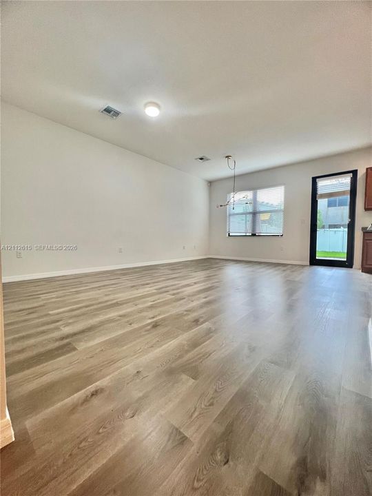 Wood-finish flooring, neutral walls, large window with natural light, and glass-paneled exterior door