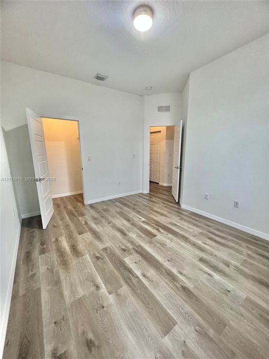 Interior space featuring wood-finish flooring, high ceilings, neutral wall tones, and two-panel interior doors