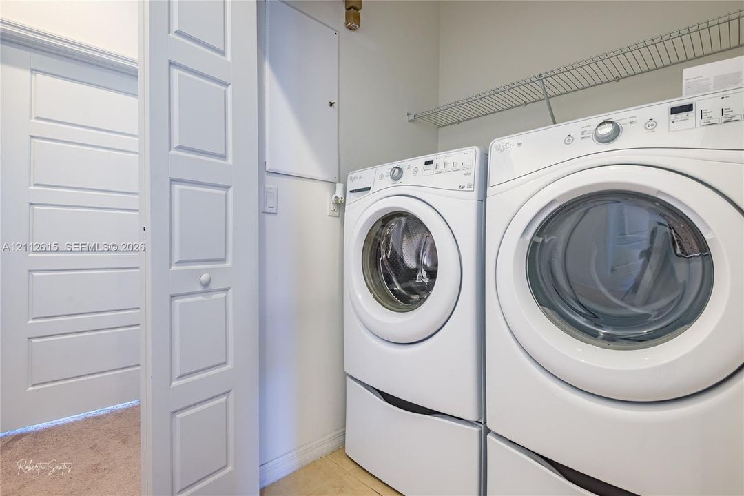 Dedicated laundry area featuring front-loading appliances, white panel door, and integrated wire shelving