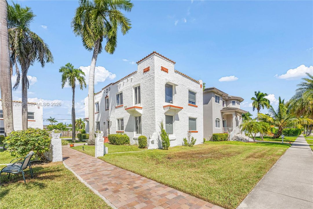 Mediterranean-inspired exterior featuring textured masonry walls, a parapet roofline with decorative corbels, and paver-stone walkways