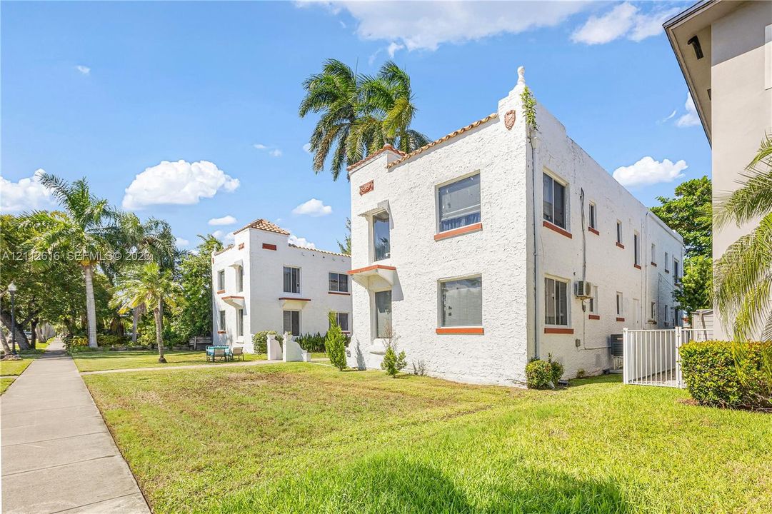 Multi-story Mediterranean-inspired architecture featuring a white textured stucco facade, clay tile accents, rectangular window casings, and decorative roofline parapets