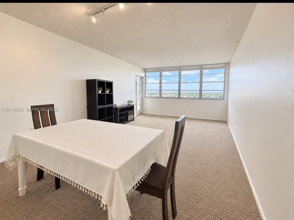 AI Image* Expansive living area featuring neutral carpeting, multi-pane floor-to-ceiling windows, and track lighting