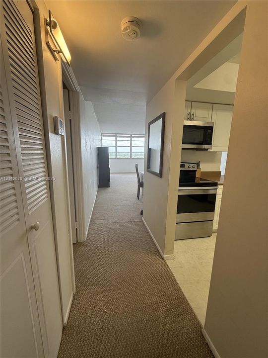Hallway featuring louvered-door closet storage, neutral carpeting